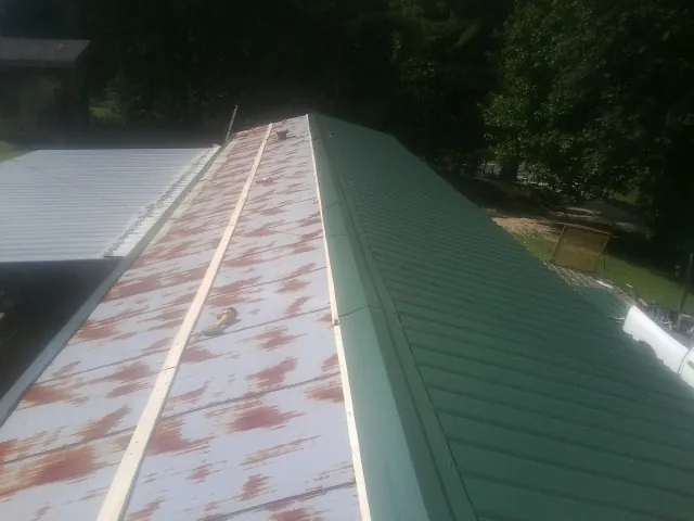 Old rusted panels beside newly installed green metal roofing — Wind Damage Roof Repair by Roofing Brothers in Old Forge
