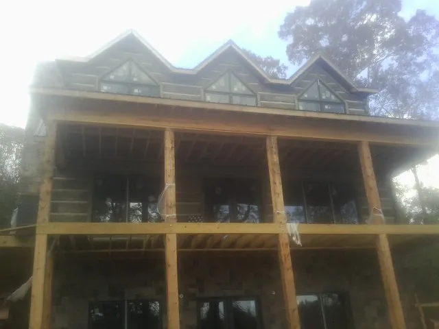 Dormers and porch framing on a large log home under construction — Roof Coating work by our crew in Old Forge