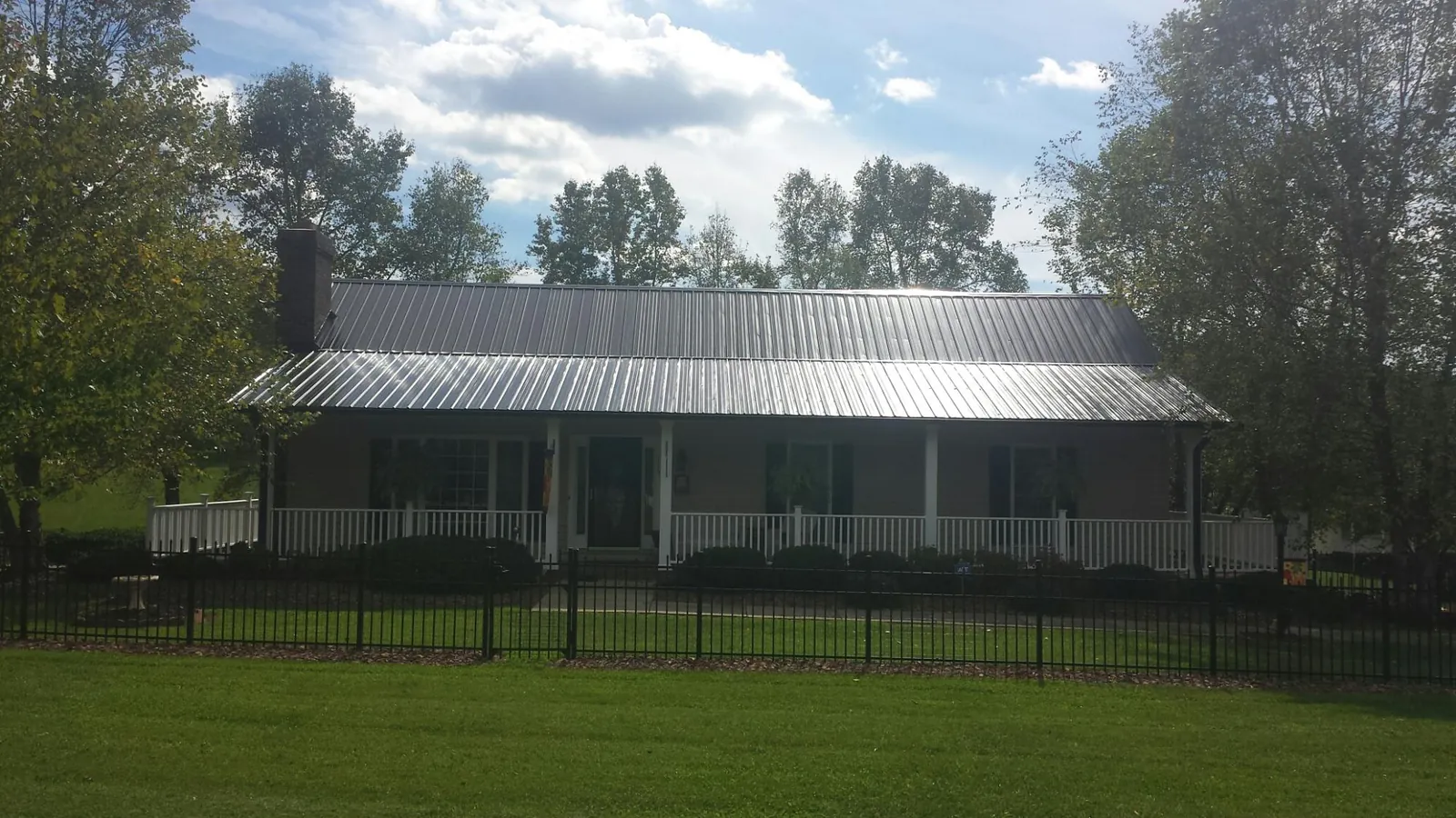 Gray metal roof on a brick ranch with a full width front porch — Gutter Guard Installation work by our crew in Old Forge