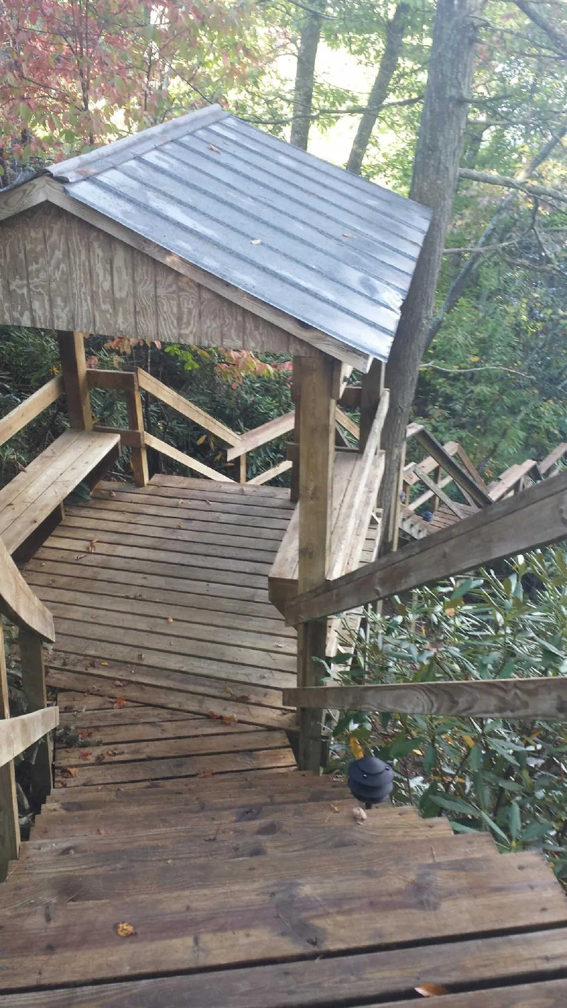 Metal roofed shelter over wooden steps on a wooded walkway — Skylight Repair & Installation work by our crew in Old Forge