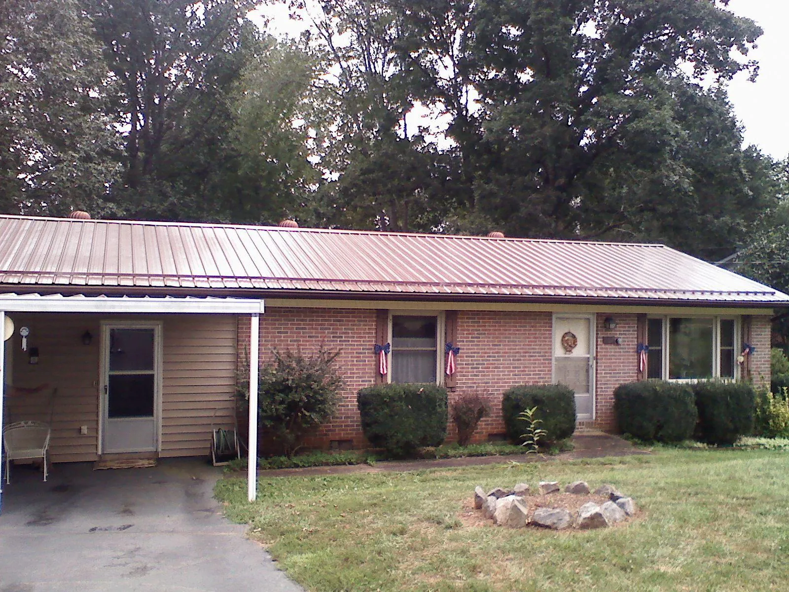 Bronze metal roof and carport on a brick ranch home — Roof Repair work by our crew in Old Forge